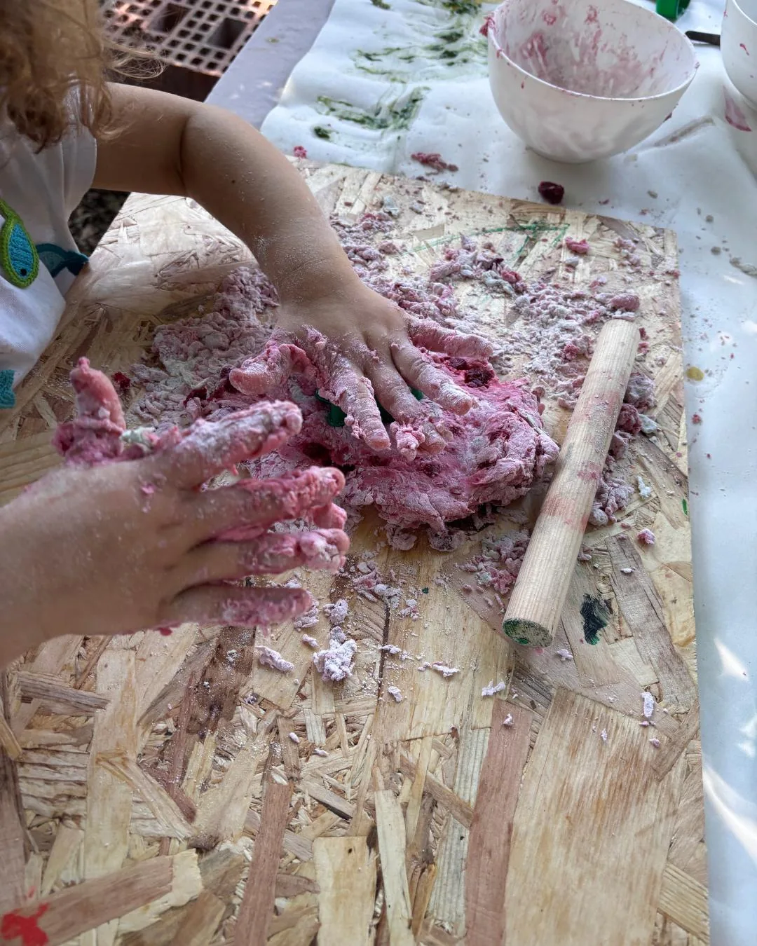 Mani di un bambino che manipola impasto rosa con pigmenti naturali