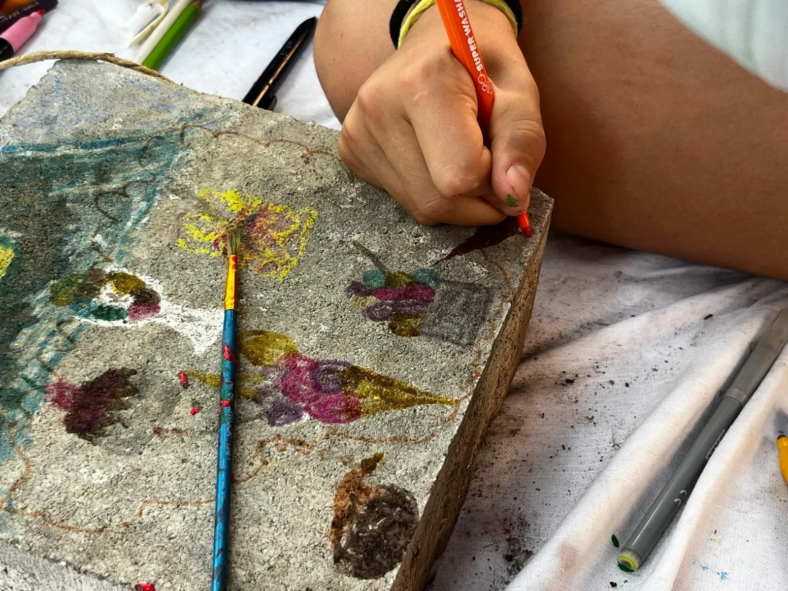 Bambino dipinge decorazioni colorate su un supporto di legno in un laboratorio creativo